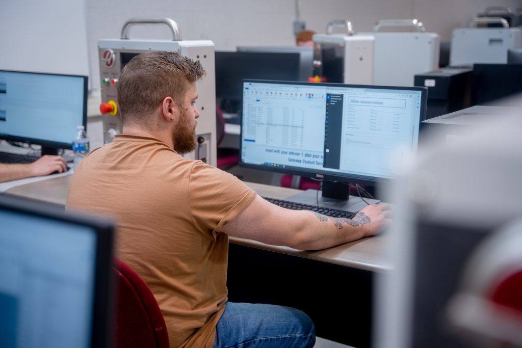 Male student sitting at large computer screen