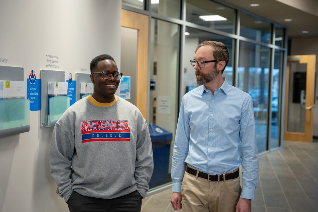Male student walking and talking with male instructor