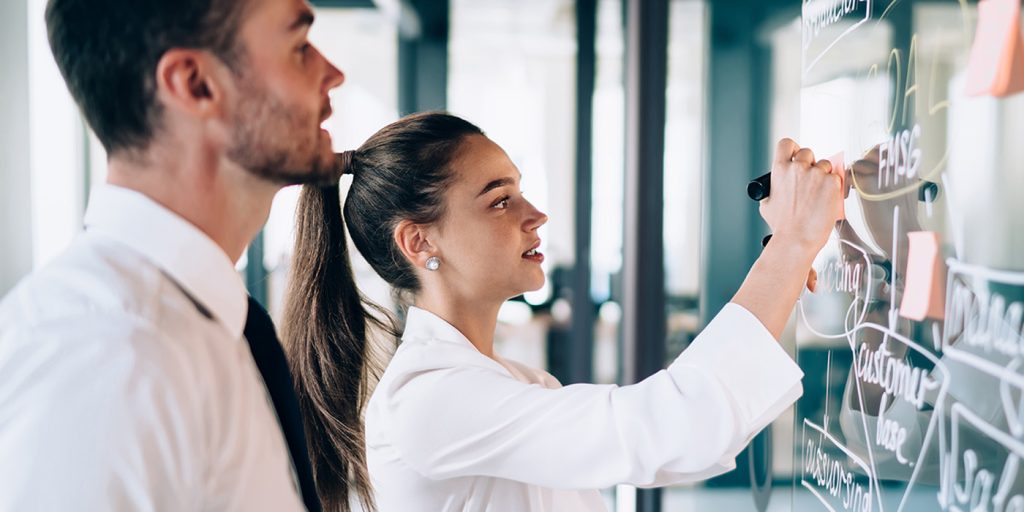 Male and female co-workers working on a smartboard together