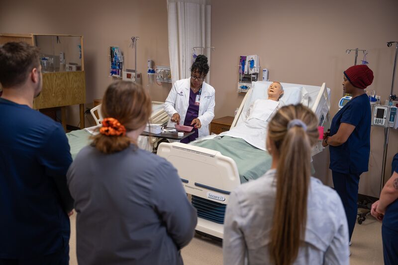 Associate degree in nursing, lab, instructor with students surrounding simulator learning