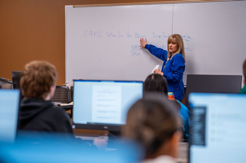 Associate degree in nursing, instructor at whiteboard teaching class, computer classroom