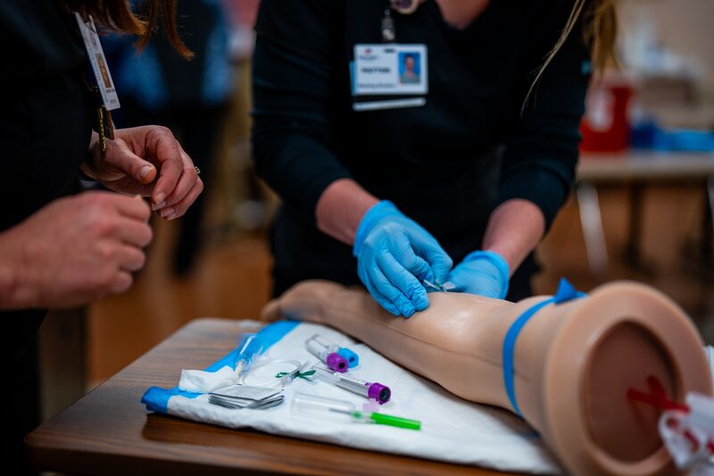Associate degree in nursing, lab, instructor with student, only see hands getting blood sample on simulator