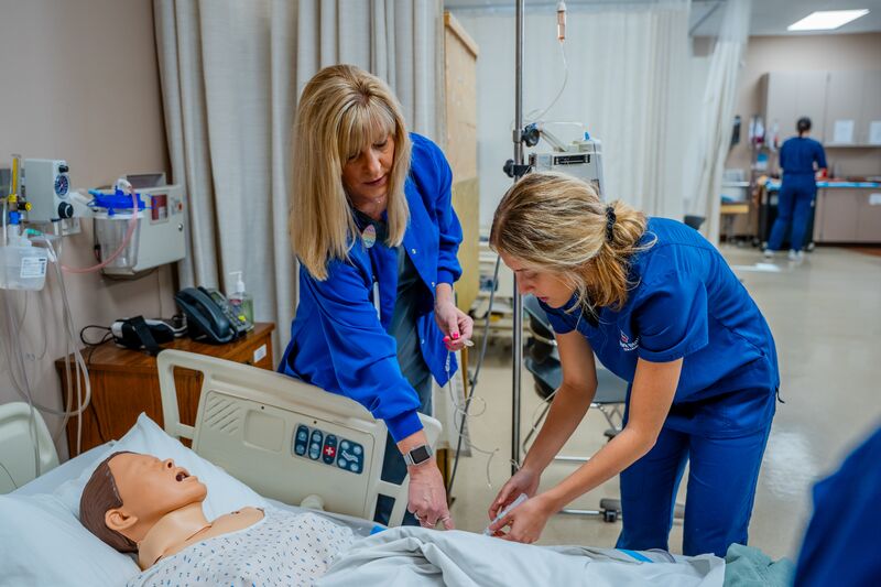 Nursing student and instructor working with nursing simulator in lab