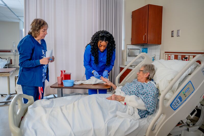 certified nurse aide (CNA), lab, female student, instructor and patient cleaning nails
