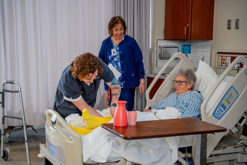 certified nurse aide (CNA), lab, male student, instructor and patient checking leg