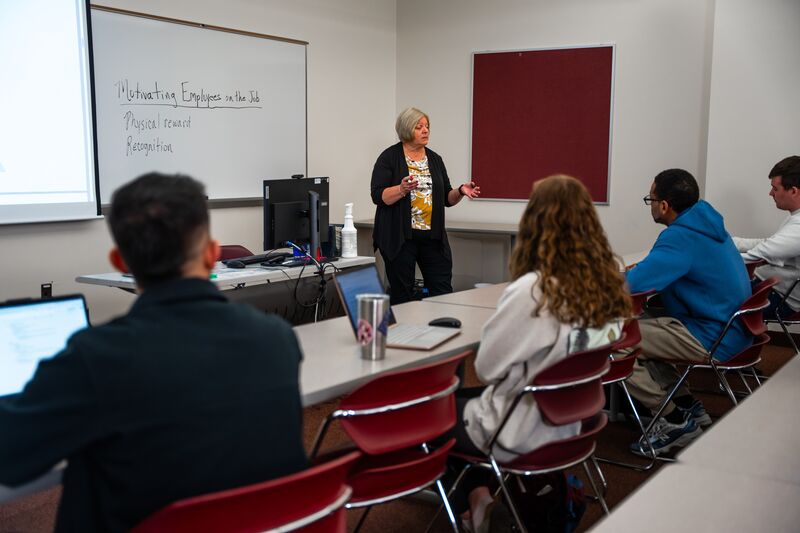 Business instructor lecturing in front of class as students listen