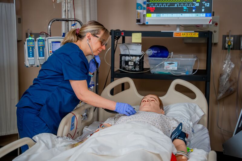 RN completion for LPN, female nursing student checking heartbeat of nursing simulator
