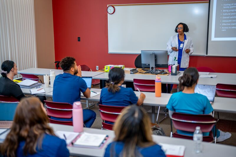 RN completion for LPN, students in traditional classroom listening to instructor lecture at front of class