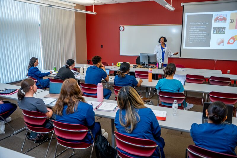 Classroom image of instructor lecturing in front of class of nursing students sitting at desks