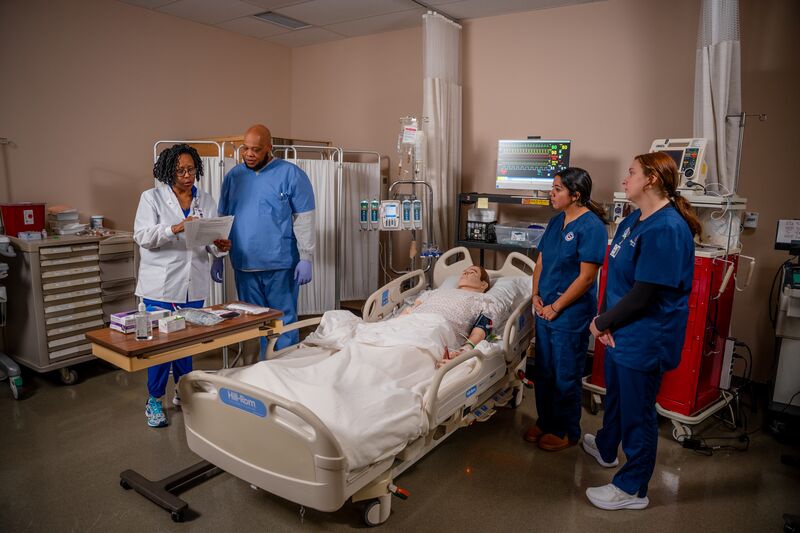 RN completion for LPN, two female students and one male student with instructor in nursing simulator lab