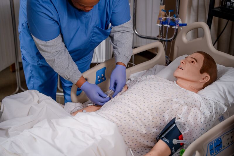 RN completion for LPN, male student adding IV to nursing simulator