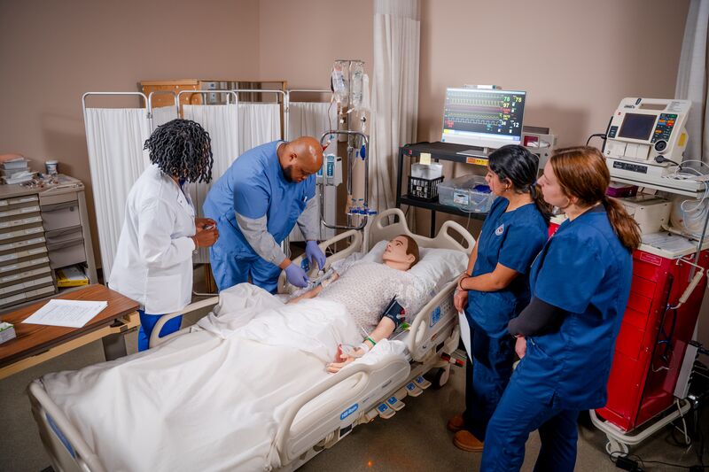 RN completion for LPN, two female students and one male student giving IV with instructor in nursing simulator lab