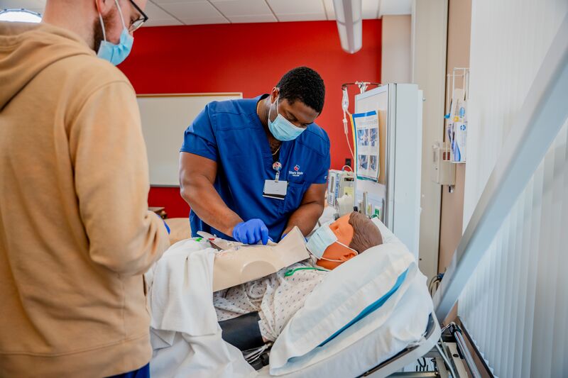 RN completion or paramedic, paramedic to RN lab, two male students working on simulator