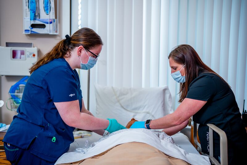 RN completion or paramedic, paramedic to RN lab, two students working on simulator