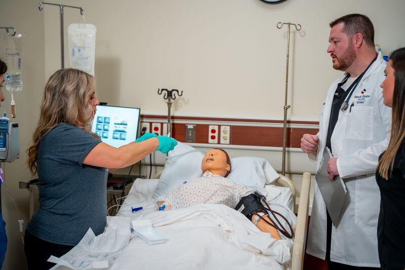 Practical Nursing, LPN, two female students working on nursing simulator with instructor watching