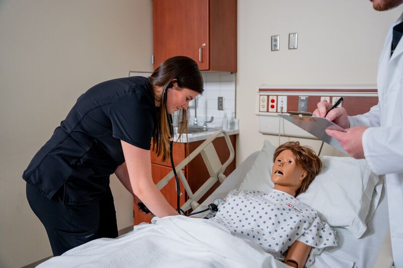 Practical Nursing, LPN, female student taking blood pressure on nursing simulator with instructor watching