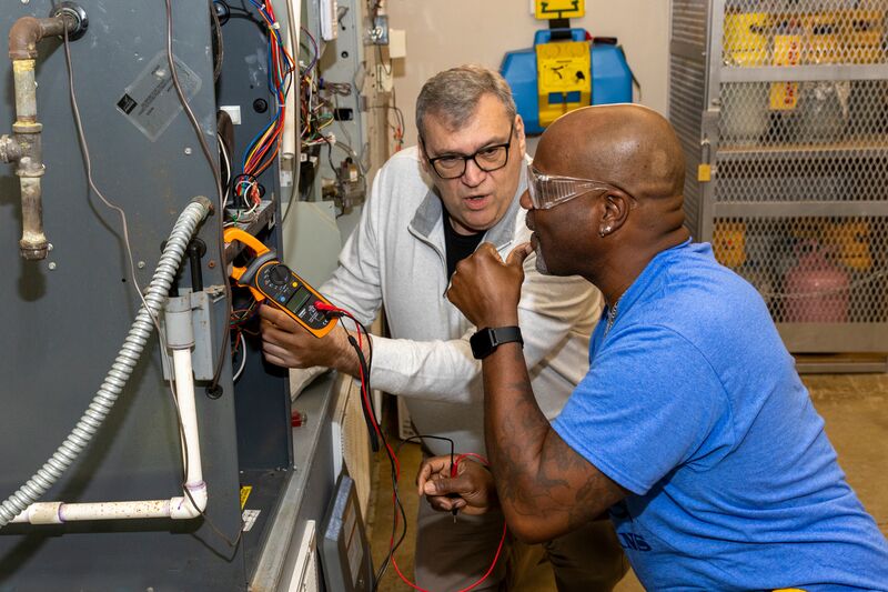 HVAC student and instructor working on an AC unit