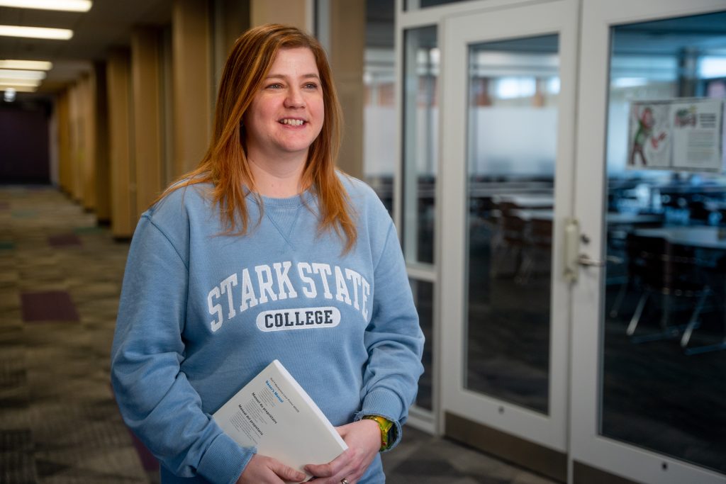 Returning students, female student wearing blue Stark State College sweatshirt smiling