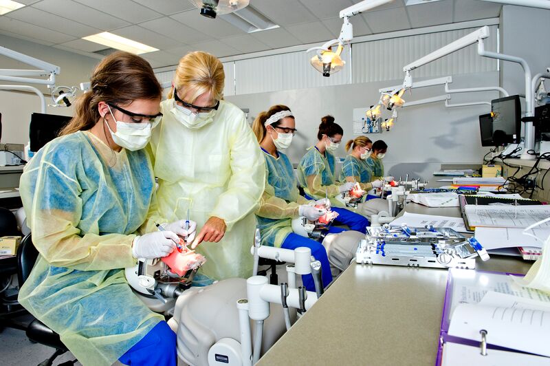Dental hygiene students working in simulator lab, instructor helping