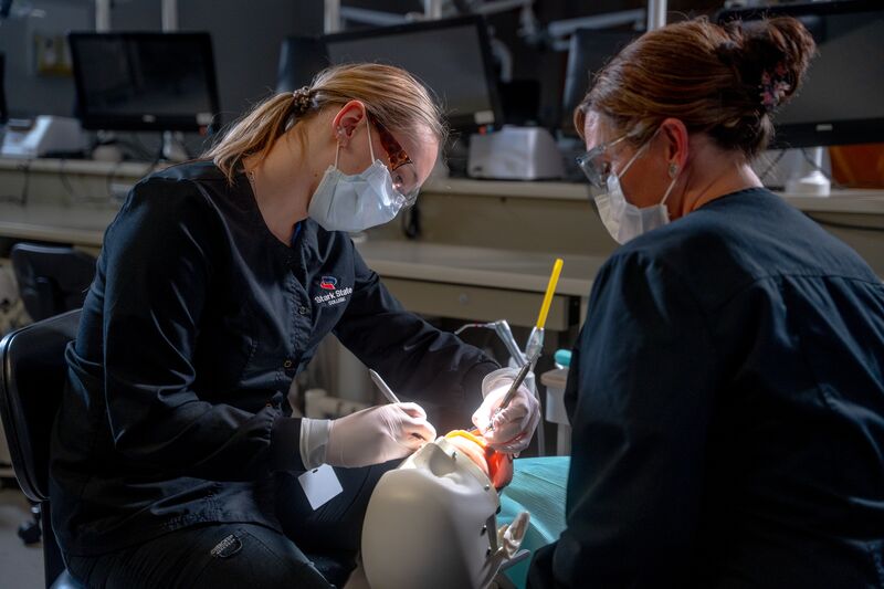 Female dental hygiene student and instructor working on simulator