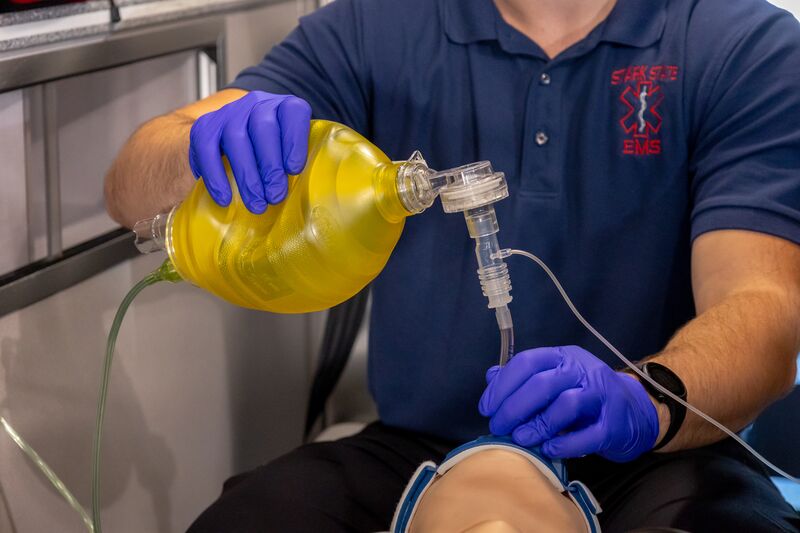 Hands of EMS student giving oxygen to simulator