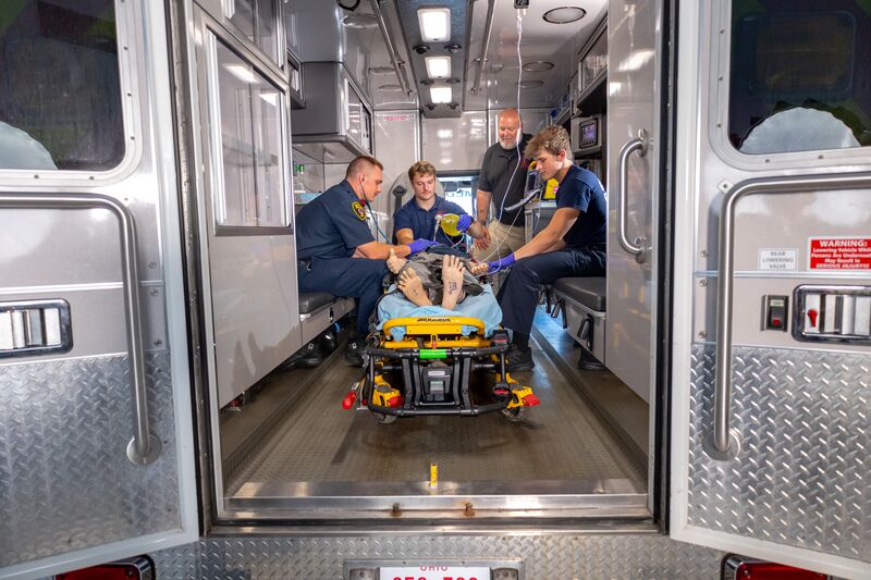 EMS students and instructor inside ambulance with simulator