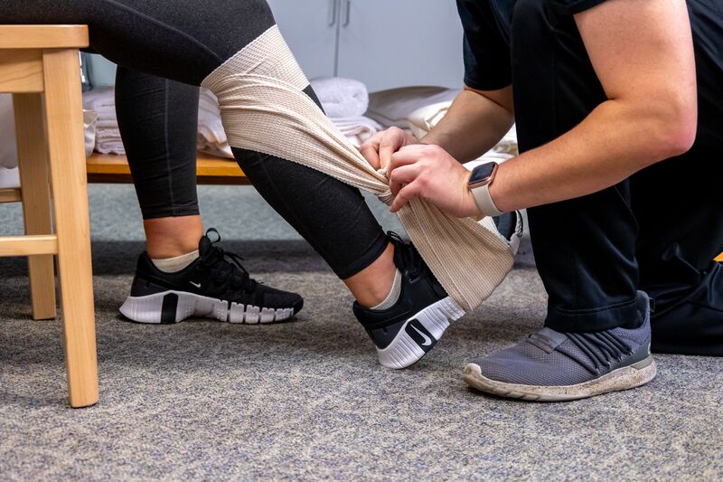 Physical therapy assisting program, hands tying knot on leg wrap