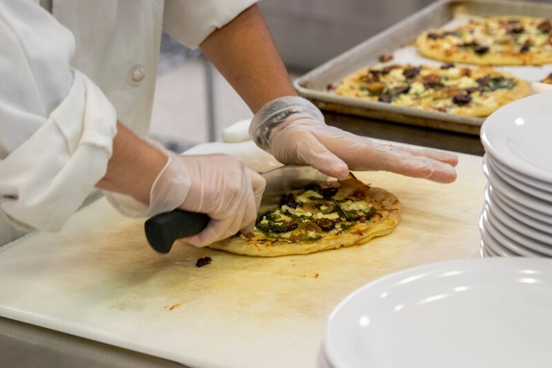 Culinary arts, hands cutting flatbread pizza