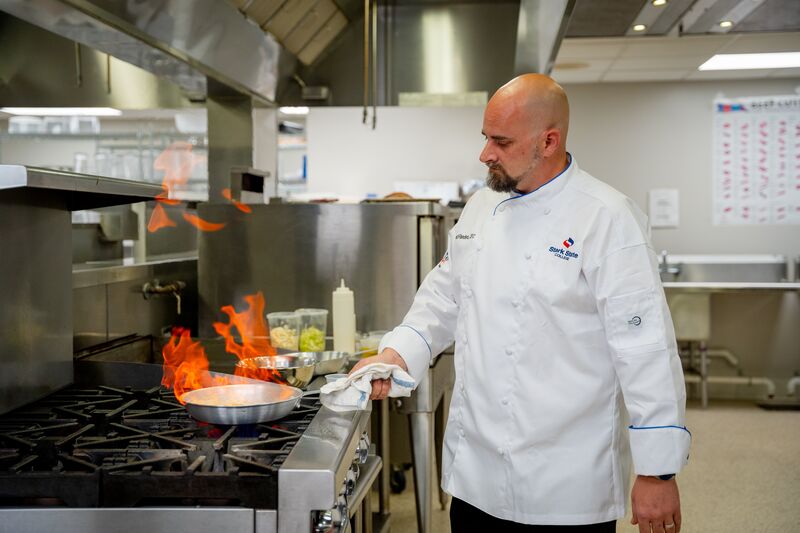 Culinary arts, male at stove, flames on pan