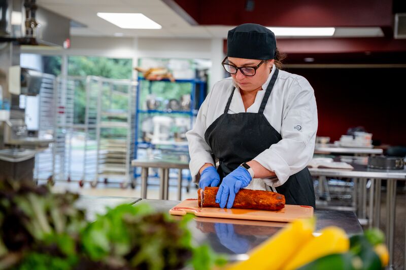 female culinary students slicing pork meat