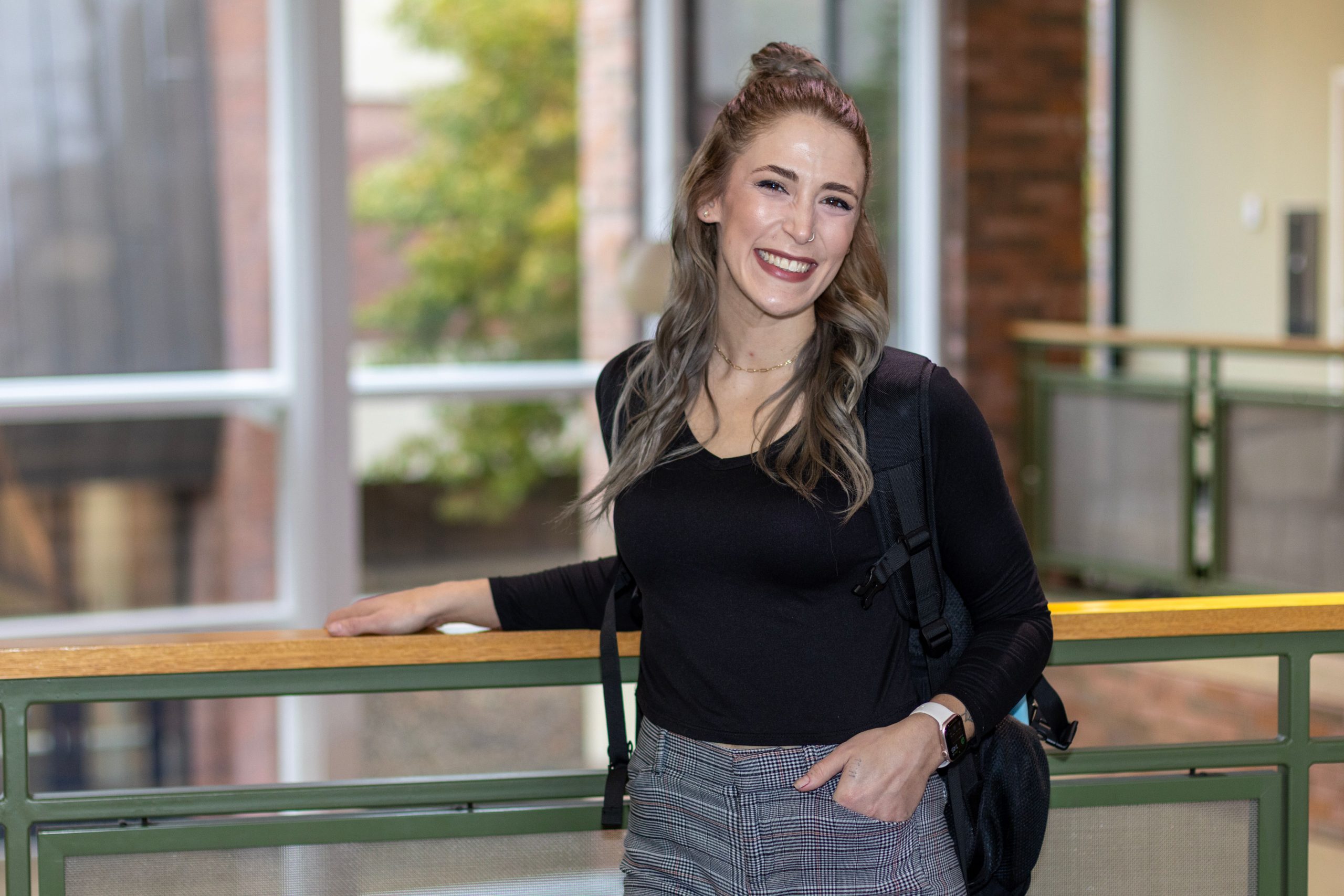 Female students, smiling, standing at wood railing