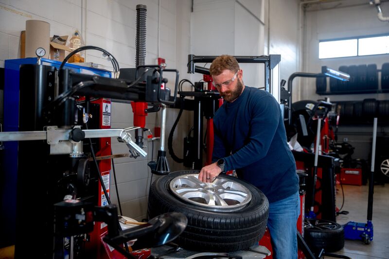 male automotive student working with tire equipment