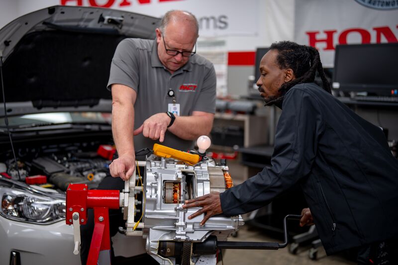 male automotive student receiving instruction from male instructor