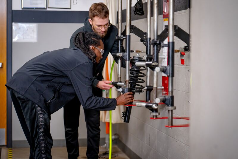 two automotive students working on springs