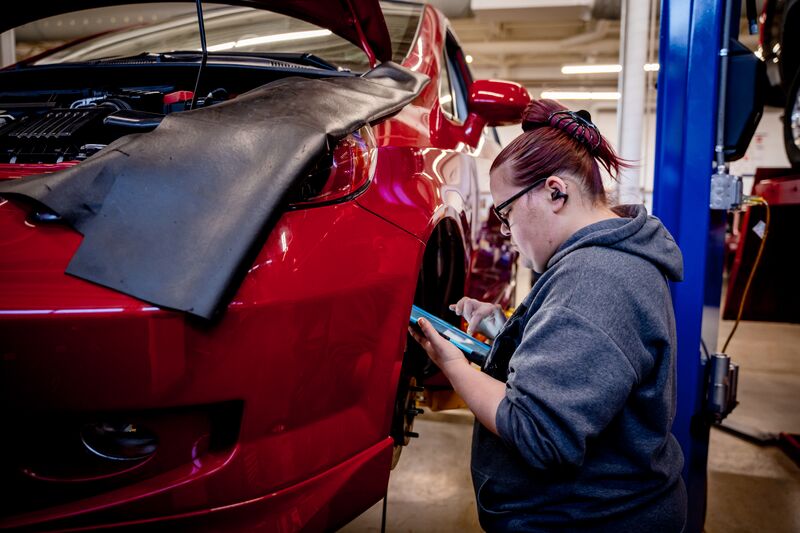 female student on tablet diagnosing car