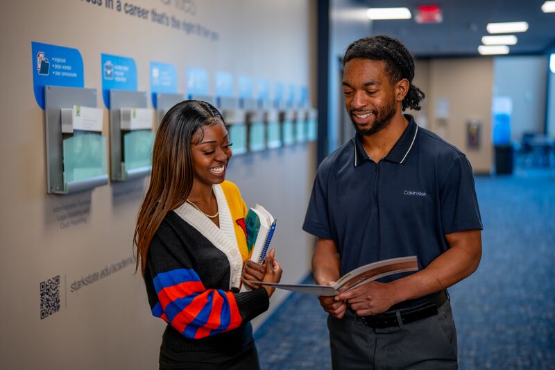 Female student talking with male advisor, holding a college brochure discussing options
