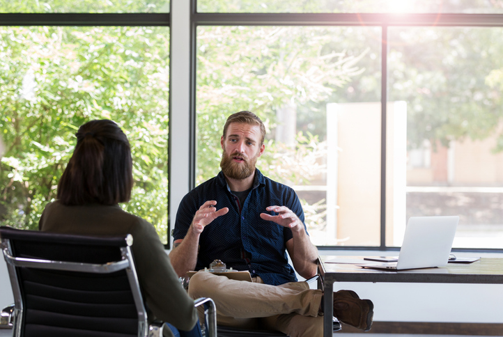 Male mental health professional gestures as he discusses an important issue with an unrecognizable female client.