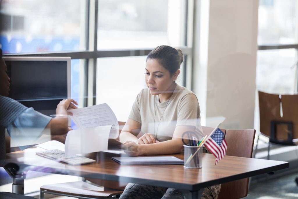 Military students, The mid adult female soldier carefully reads the loan paperwork as the unrecognizable banker explains everything.