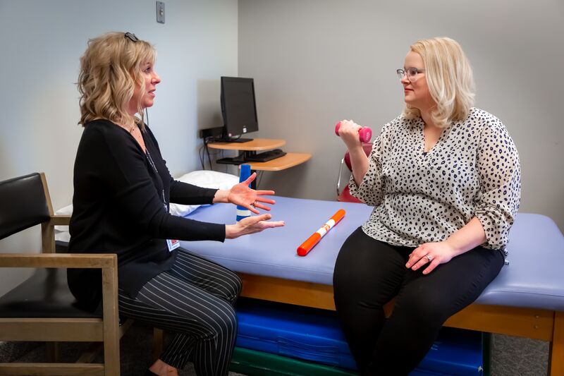 Occupational therapy, instructor and student working with small weights for arm motion