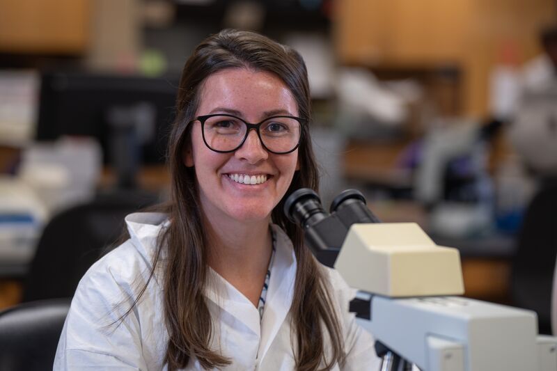 Medical laboratory, female student smiling at microscope