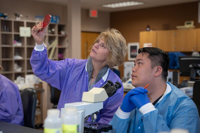 Medical laboratory, male student and female instructor look a sample