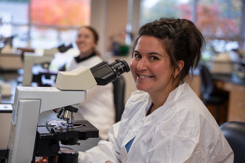 Medical laboratory, female student smiling at microscope